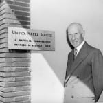 Jim Casey stands next to the United Parcel Service wall plaque in Seattle in 1952. Photo courtesy of UPS archives.